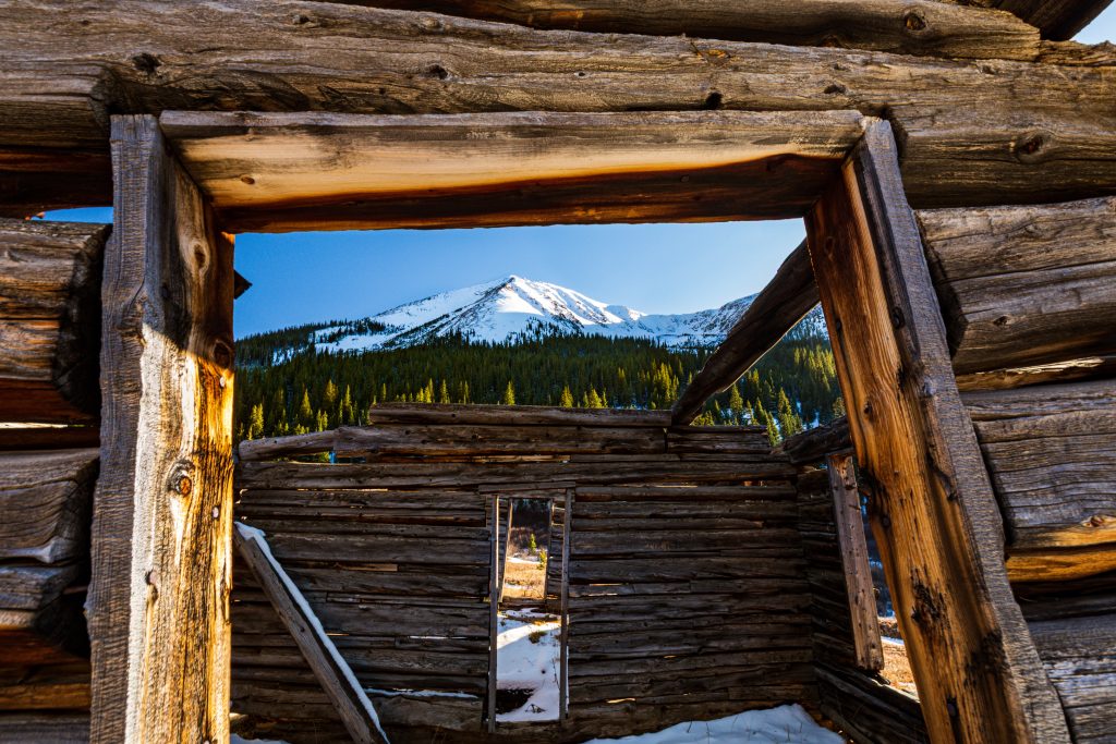 5DM40371 Photo of snow-covered mountain framed by open front door of ghost town building